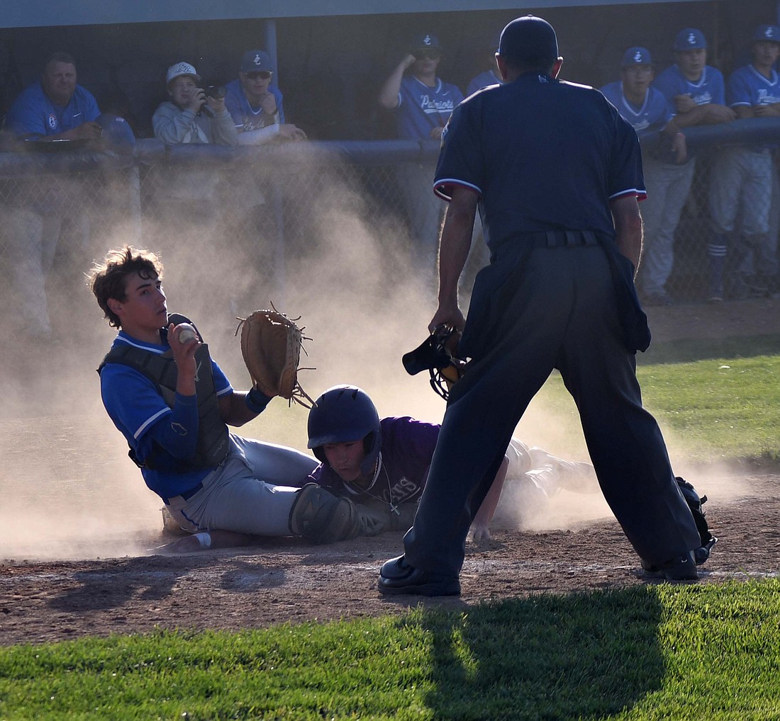 Jay County High School catcher Drew Schemenaur shows the home plate umpire the ball after tagging out Muncie Central’s Kye Hiatt on a throw from center fielder Cody Rowles on Monday. The Patriots beat the Bearcats 11-1 to bounce back from three straight losses. (The Commercial Review/Andrew Balko)