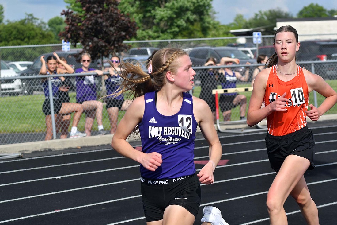 Natalie Brunswick, a senior on the Fort Recovery High School girls track team, looks back to judge her lead on Minster’s Maria Niekamp during the 3,200-meter run Friday at the OHSAA Division III district meet at Spencerville. Brunswick pulled away with about 500 meters left in the race to claim her second district title with a time of 12 minutes, 0.56 seconds. (The Commercial Review/Andrew Balko)