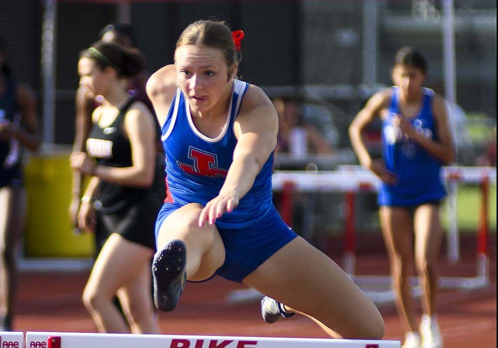 Jay County High School’s Morgan DeHoff leaps over a hurdle during the regional meet at Pike on Tuesday. DeHoff climbed to 14th place in the 100-meter hurdles with a time of 18.55 seconds. (The Commercial Review/Ray Cooney)