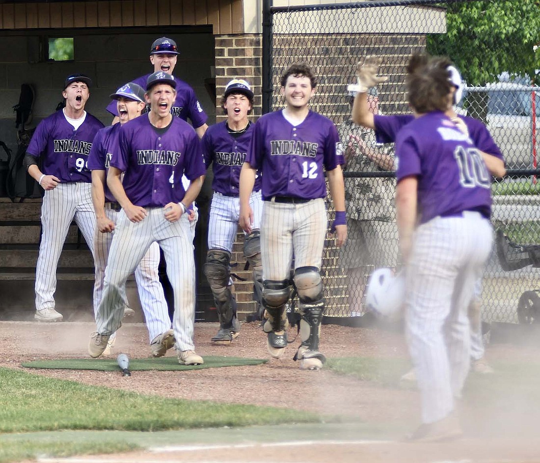 The Fort Recovery Indians come out of their dugout to celebrate with Caden Homan (10) after he scored to give them a 4-0 lead in the third inning of Friday’s Division IV district championship game at Coldwater. The Tribe added seven runs in the fifth inning as it rolled to its first district title since 2016. (The Commercial Review/Ray Cooney)