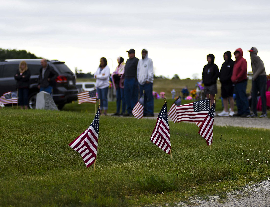 Flags line the center circle of Hillcrest Cemetery south of Redkey as a group gathers for the Memorial Day Service late Monday morning. The event included James Fulks, who led the ceremony, acknowledging World War II veteran Herb Heston, who was in attendance. (The Commercial Review/Ray Cooney)