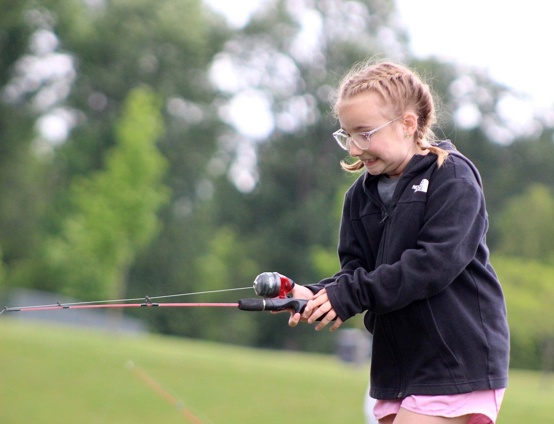 Kieara Lambert, 7, juggles her fishing rod Wednesday at Hudson Family Park. Kieara Lambert, her 5-year-old sister Zoey Lambert, and other friends spent their day fishing with their mothers and playing at the park. (The Commercial Review/Bailey Cline)