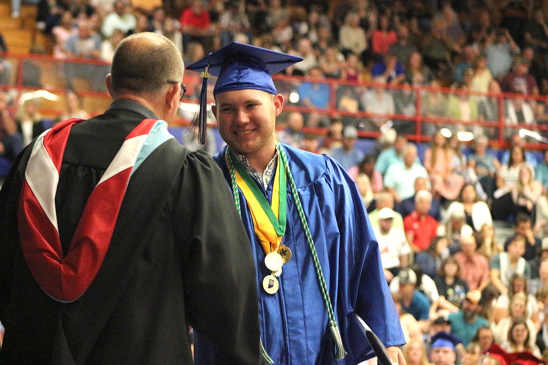 Ryne Goldsworthy shakes hands with Jay County High School principal Chad Dodd after receiving his diploma Sunday. Goldsworthy was one of 208 members of the Class of 2024 to receive a diploma. (The Commercial Review/Bailey Cline)