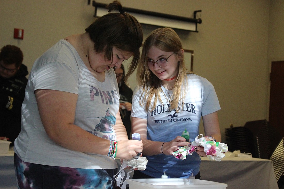 Jaidan Agler, 13, and Mary Garringer, 13, dye canvas tote bags Tuesday during Jay County Public Library’s Teen Tie-Dye Hour event. The library has various activities planned this summer, including an interactive “Toy Story” movie experience at 2 p.m. Friday. (The Commercial Review/Bailey Cline)