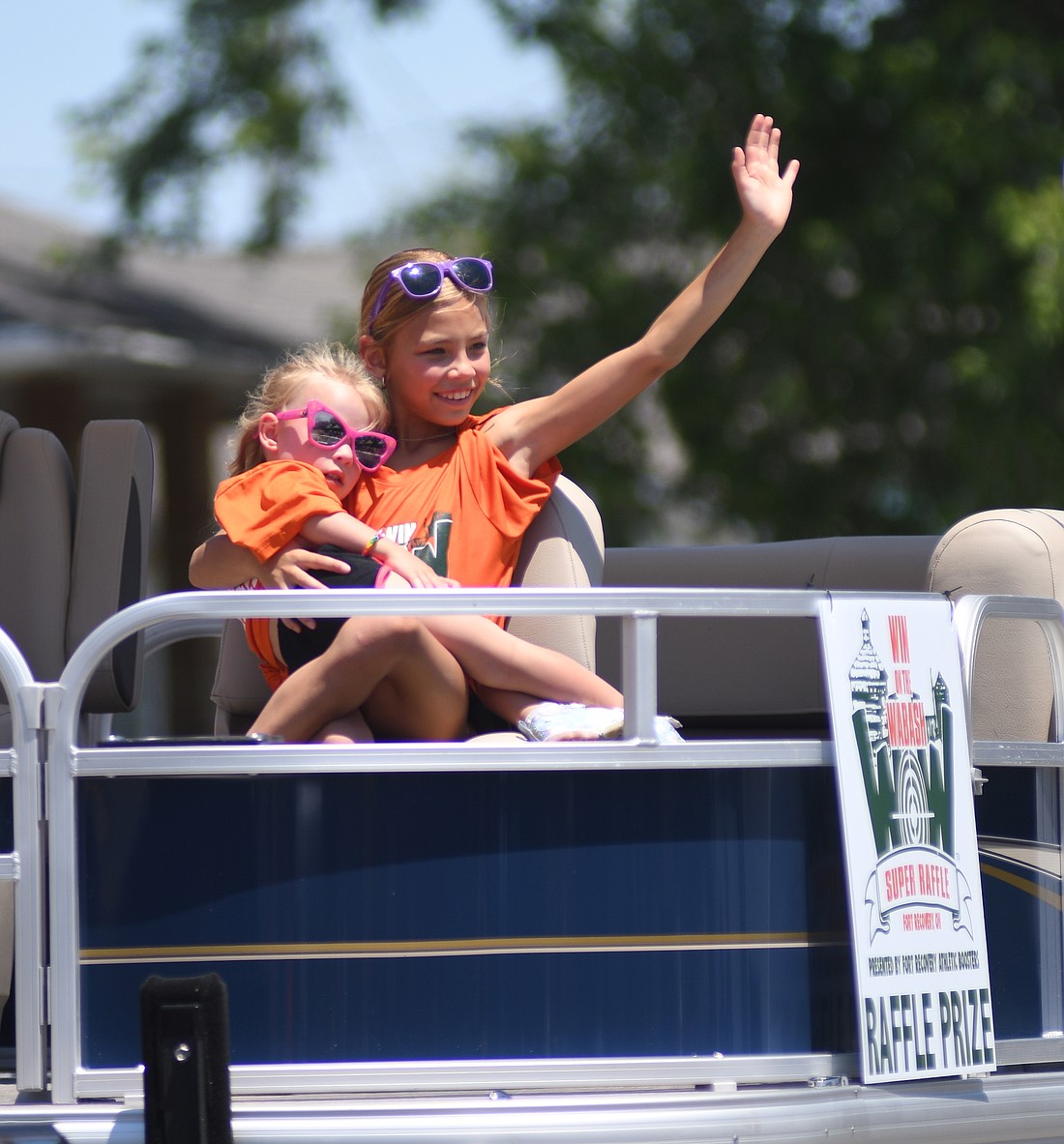 Cierra Gaerke waves to paradegoers along Butler Street on Sunday afternoon while riding on one of the Win on the Wabash super raffle vehicles during the Fireman’s Parade as part of the Fort Recovery Harvest Jubilee. (The Commercial Review/Ray Cooney)