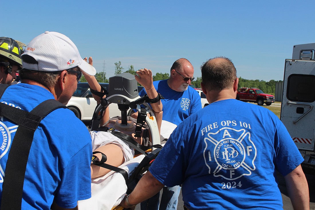 Portland Fire Department hosted its first Fire Ops 101 training for local and state officials and media personnel Saturday. Pictured above, Duane Monroe — he’s the Republican nominee for the south district Jay County Commissioner seat up for election in November — Portland Board of Works member Steve McIntosh and Portland attorney Greg LeMaster carry a mannequin onto a Jay Emergency Medical Service ambulance Saturday. Participants experienced live fire suppression, search and rescue, vehicle extrication and a cardiac arrest event simulation. (The Commercial Review/Bailey Cline)