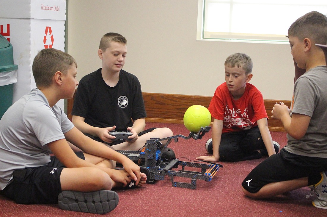 Bentley Brunswick, 12, Jake Arnold, 12, Owen Clemens, 10, and Gabe Lutz, 10, practice launching a ball with their robot Wednesday during the 2024 VEX Robotics morning camp at John Jay Center for Learning. Participants built robots to compete in VEX Robotics’ latest game, Rapid Relay, at the end of the week. (The Commercial Review/Bailey Cline)