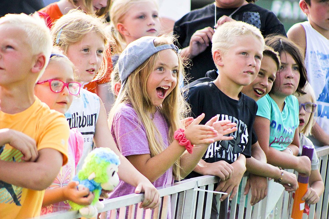 Evie Brelsford, 6, center, claps while watching a dinosaur performer in the Stone Age entertainment area Monday. (The Commercial Review/Bailey Cline)