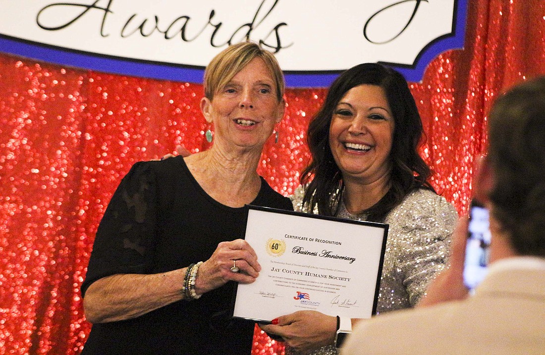 Jay County Chamber of Commerce executive director Tabby Sprunger poses for a pictured with Mindy Weaver after presenting her with an anniversary certificate for Jay County Humane Society during the Jay County Community Awards in May as Nick Lyons (foreground) takes a photo. The chamber’s board of directors announced Thursday morning that Sprunger will be leaving her role as executive director to accept a new job. She will start in her new role Monday but plans to continue with the chamber until a new executive director is hired. (The Commercial Review/Bailey Cline)