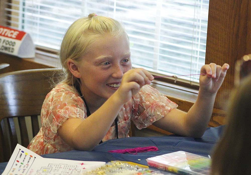 Addalyn Wentz, 9, shows off the start of her friendship bracelet Tuesday during Jay County Public Library’s A Night for the Swifties event. Stations were set up around the library themed after Taylor Swift, including the friendship bracelet station themed after Swift’s 10th album, “Midnights.” (The Commercial Review/Bailey Cline)