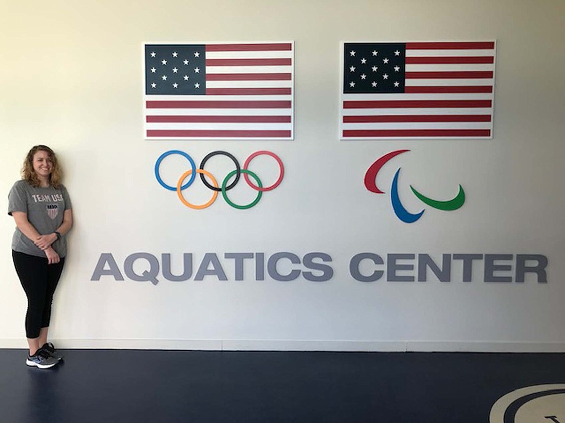 Laura Bowen, a Jay County native, stands next to sign Olympic and Paralympic logs at the Aquatics Center of the Colorado Springs Olympic & Paralympic Training Center. Bowen has been working as the Coordinator of Aquatic Operations at the training center since Dec. 2021 and described it as her “dream job.” (Photo provided)