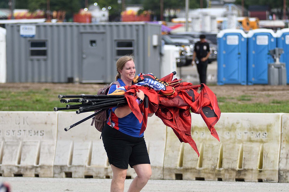 Emilie Garringer, Jay County’s assistant director, hauls an armful of flags off of the track following the Marching Patriots’ morning performance. (The Commercial Review/Ray Cooney)