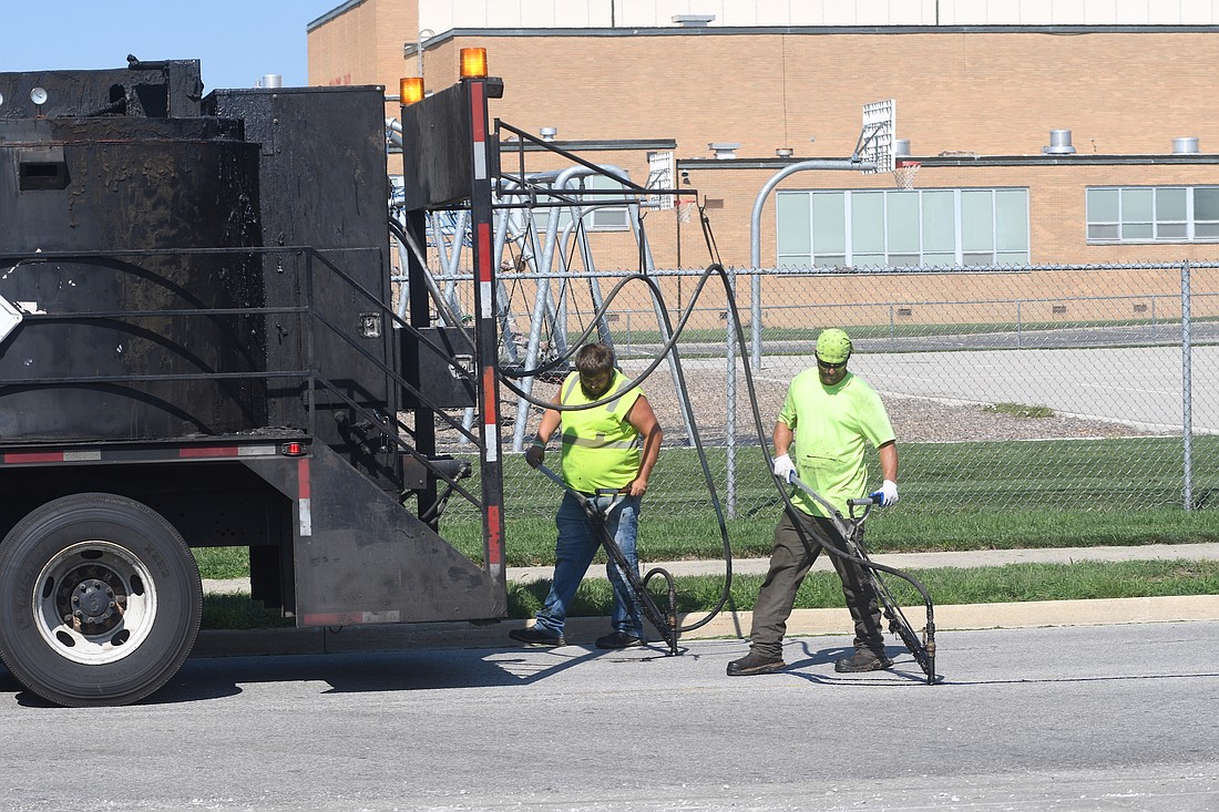 Workers from Scodeller Construction of Wixom, Michigan, seal cracks along Wayne Street just south of Water Street near East Jay Elementary School in Portland. The work is part of an ongoing project to seal cracks in streets throughout the city. The work is largely funded via a $153,164.10 Community Crossings grant through Indiana Department of Transportation. (The Commercial Review/Ray Cooney)