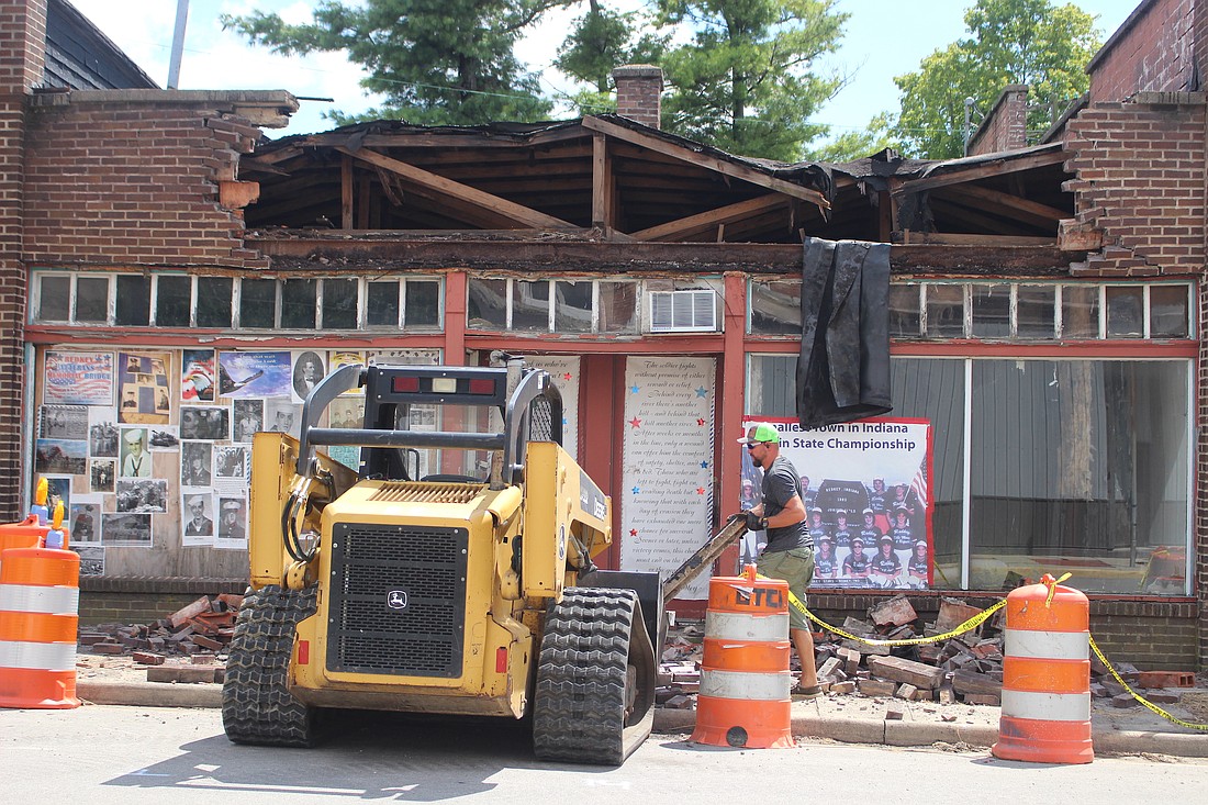 The front brick portion of the building at the southeast corner of High and Union streets in Redkey partially collapsed Thursday evening. Pictured above, Ryan Sutton, stepson to property owner Glynn Barber, clears debris from the sidewalk on the north side of the building Friday afternoon. (The Commercial Review/Bailey Cline)