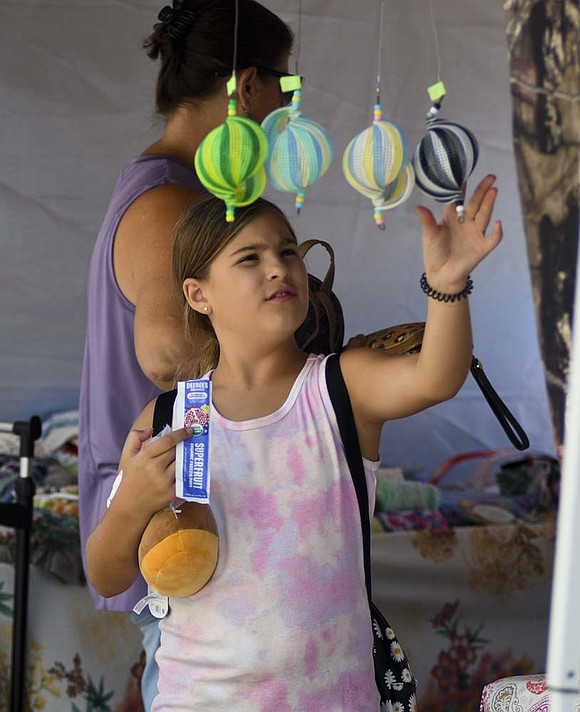 Ava Hackworth, 8, Huntington, checks out one of the vendor’s offerings during the Glass Days festival Saturday afternoon in Dunkirk. The event featured various vendors and glass artisans. (The Commercial Review/Ray Cooney)