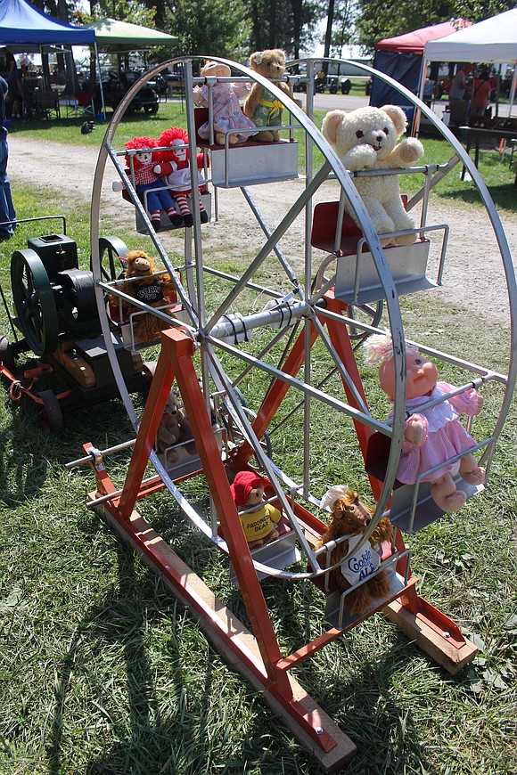 Stuffed toys and dolls ride a Ferris wheel powered by Cloverdale resident Neil McCammack’s Foos Junior antique gas engine Friday morning at the fairgrounds. (The Commercial Review/Bailey Cline)