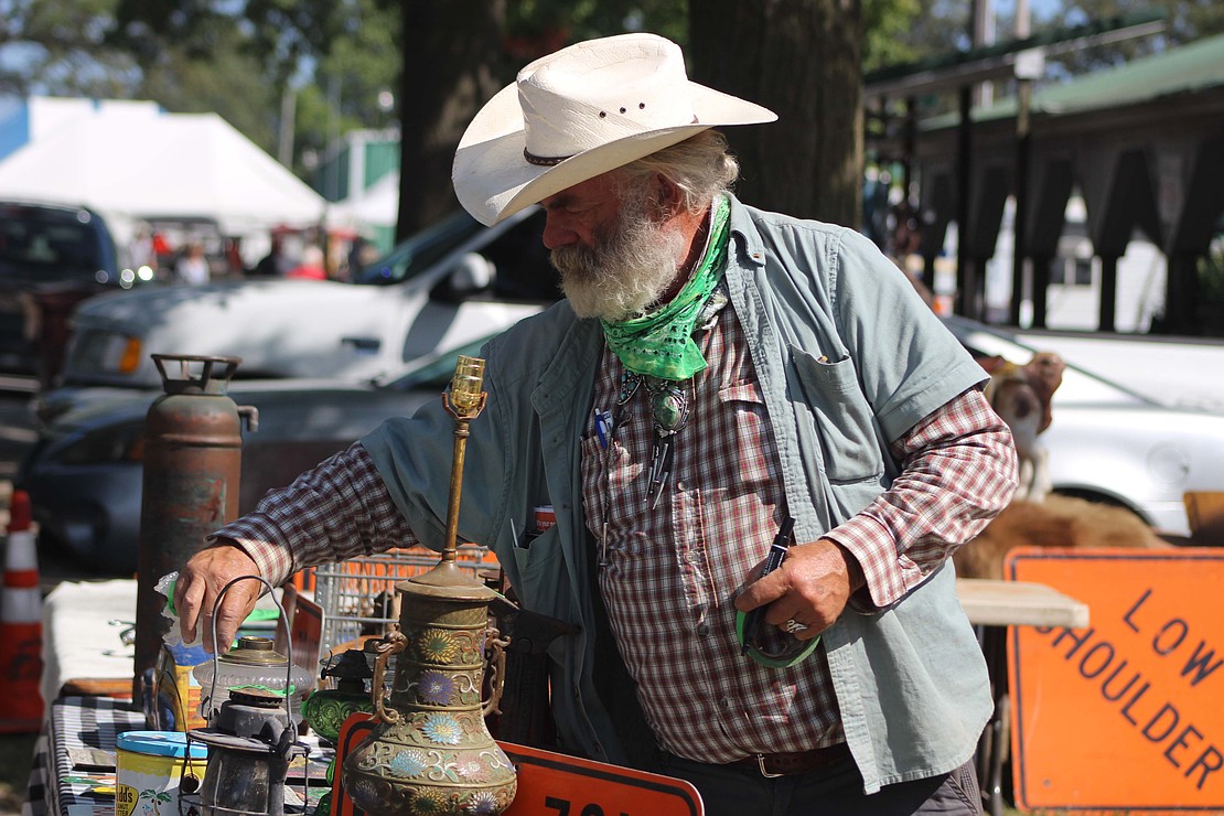 Business was booming Friday at the Tri-State Antique Engine and Tractor Show in Portland. Pictured, John Hughes of Texas marks prices on his merchandise with green duct tape Friday morning near Floral Hall. (The Commercial Review/Bailey Cline)