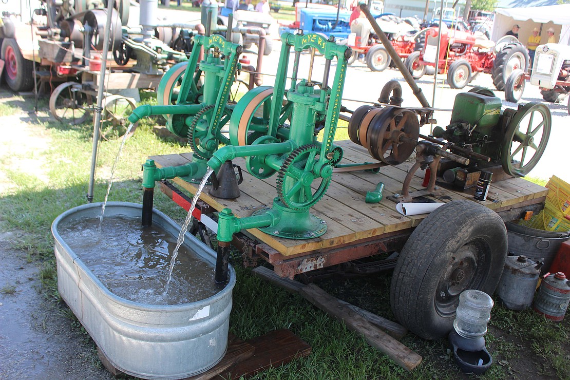 Two 1915 F.E. Myers pumps powered by a 1930 John Deere — the mechanism is owned by Marvin Rees — pour water into a basin Friday afternoon at the fairgrounds. (The Commercial Review/Bailey Cline)