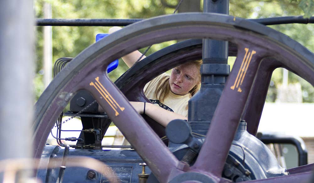 Stella Tumbleson, 14, of Wells County pours oil into a Muncie Oil Engine Company engine while working with her family on the machine Saturday during the Tri-State Antique Engine and Tractor Show at Jay County Fairgrounds. The 59th annual event closed Saturday. (The Commercial Review/Ray Cooney)