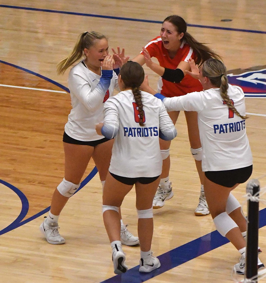 Jay County High School’s Lani Muhlenkamp (8) gets swarmed by teammates Brenna Bailey (libero), Paisley Fugiett (7) and Kayla Jetmore (6) after her pass over the net during a scramble resulted in the final kill of the third set for a 25-17 win over Winchester. The Patriots walked away with the 25-17, 20-25, 25-17, 25-10 victory Tuesday over the Golden Falcons. (The Commercial Review/Andrew Balko)