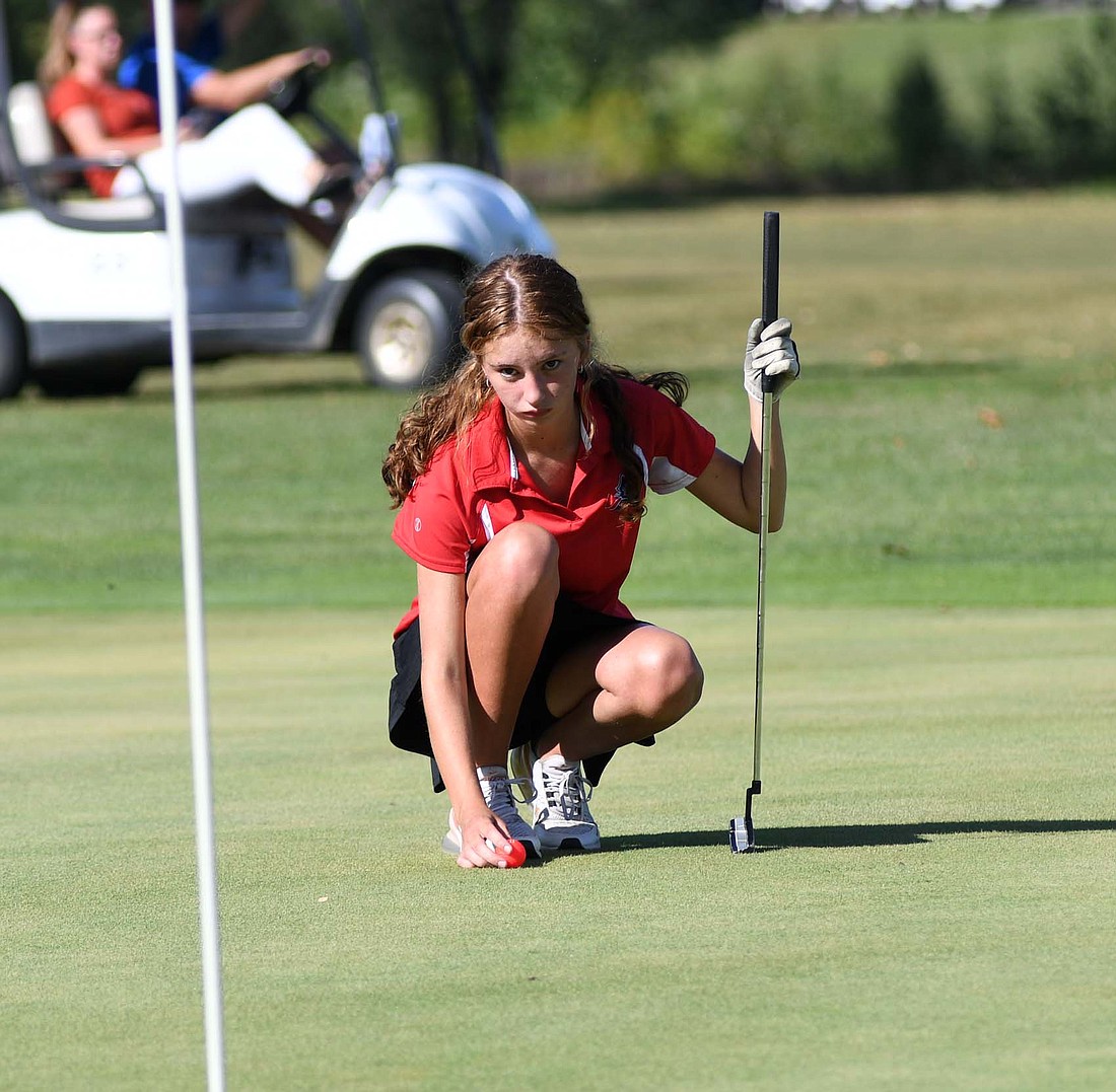 Jay County High School freshman Bailey Towell places her ball while reading her line at Portland Golf Club on Tuesday. Towell shot a career best 49, but JCHS couldn’t manage a win against Fort Recovery or Winchester. (The Commercial Review/Ray Cooney)