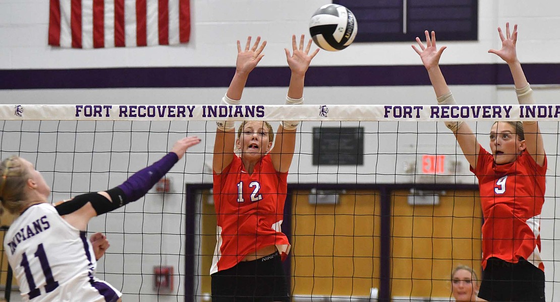 Jay County’s Maria Hemmelgarn (12) and Brenna Schmiesing (9) rise up for a block attempt on Kennedy Muhlenkamp of Fort Recovery. (The Commercial Review/Andrew Balko)