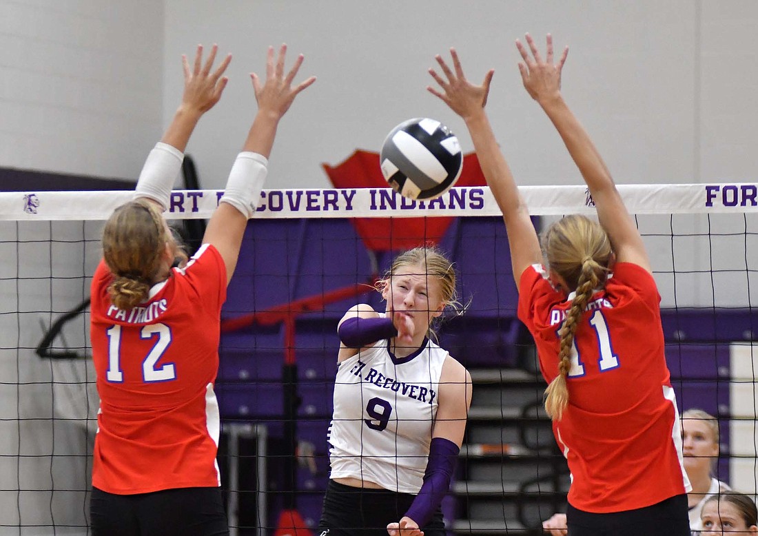 An attack from Fort Recovery High School’s Brynn Willmann splits Maria Hemmelgarn (12) and Mya Kunkler (11) of Jay County during Tuesday’s match. Willmann had six kills and three blocks in the three-set sweep. (The Commercial Review/Andrew Balko)