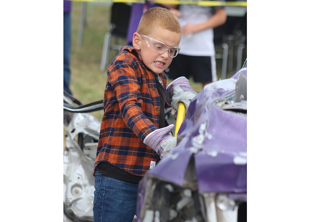 JT Steinbrunner, 6, takes a whack at a vehicle during Holy Cross Family of Parishes’ tailgate Friday prior to the football game at Barrenbrugge Athletic Park in Fort Recovery. The tailgate  featured music, games food trucks, a raffle and a car smash fundraiser. (The Commercial Review/Bailey Cline)