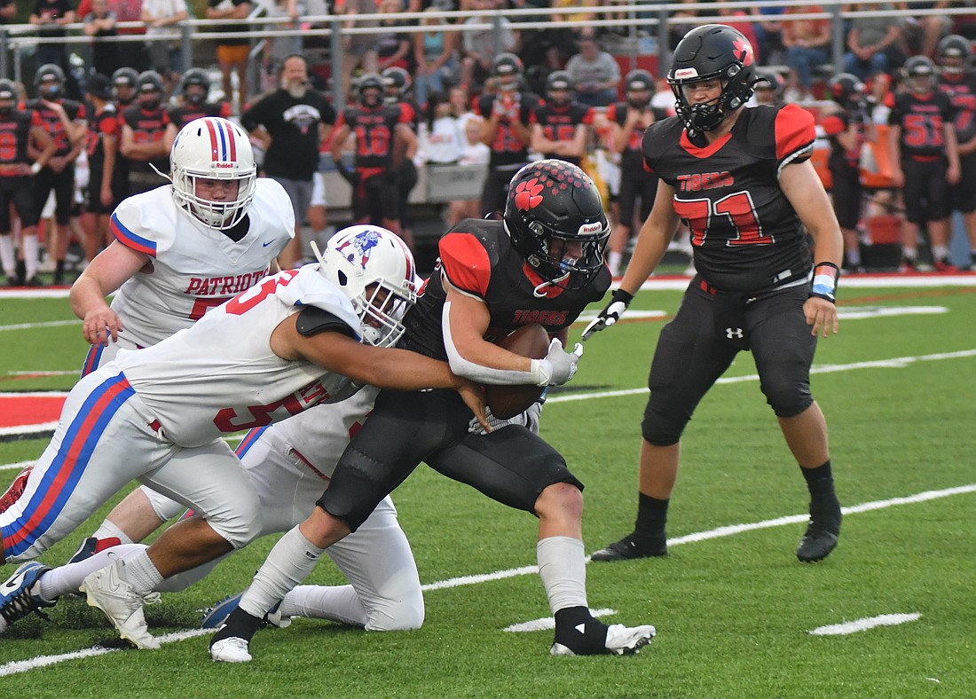 Jay County High School junior Joaquin Johnson and another Patriot defender wrap up Bluffton running back Cooper Craig during the Patriots’ 34-25 loss to the ninth-ranked team in Class 2A on Friday. Craig finished the game with 102 rushing yards and 84 receiving yards. (The Commercial Review/Andrew Balko)