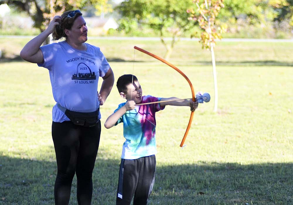 Jameson Burrough, 7, of Dunkirk tries his hand with archery alongside his mom Stephanie on Saturday morning during the Walk in the Park. The event led by West Jay Optimist Club highlighted the new walking trail at Dunkirk City Park. Optimist members set up stations along the trail with various giveaways and activities. (The Commercial Review/Ray Cooney)