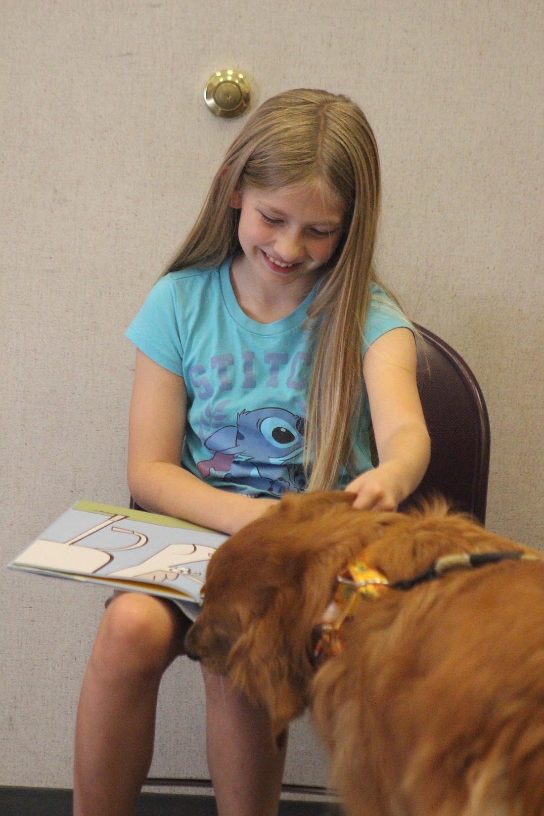 Kennedy Newell, 10, reads to Rusty during the Paws and Pages event Thursday evening at Jay County Public Library. Certified therapy dogs visited the library, allowing children to read to them and play with them. (The Commercial Review/Bailey Cline)