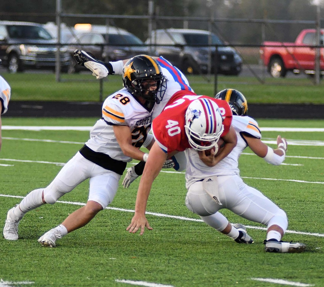 Isaac Dues, a senior at Jay County, flips over a pair of defenders on a 5-yard rush to open the game Friday. Jay County had 81 more yards on 36 more plays, but South Adams found the end zone three more times for a 34-14 victory. (The Commercial Review/Andrew Balko)