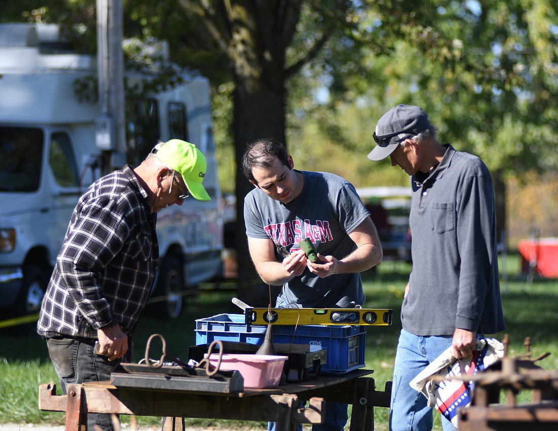 Father and son Shawn and Dave Phillips (center and right) look Thursday morning at some of the items Don Marchal of Versailles, Ohio, has set up at the Tri-State Gas Engine and Tractor Association Swap and Sell Meet. The meet at the Tri-State grounds, 1010 N. Morton St., Portland, continues today and Saturday. Admission is $5, with those younger than 12 admitted free. (The Commercial Review/Ray Cooney)