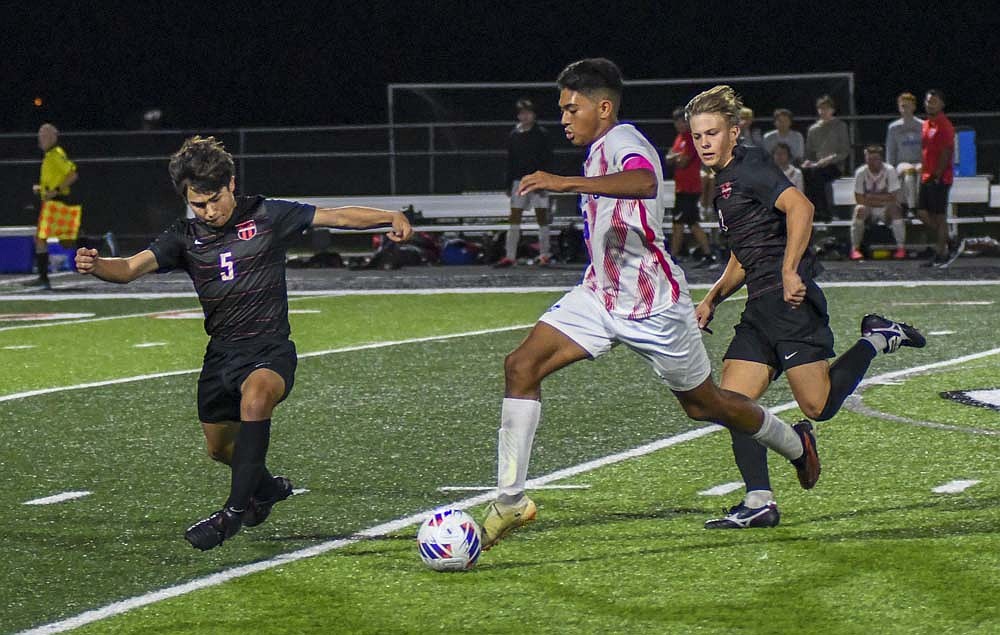 Dylan Marentes dribbles through a pair of defenders during the sectional championship game against Eastbrook on Saturday. The Patriots will need a similar performance to advance to Saturday’s regional championship. (The Commercial Review/Ray Cooney)