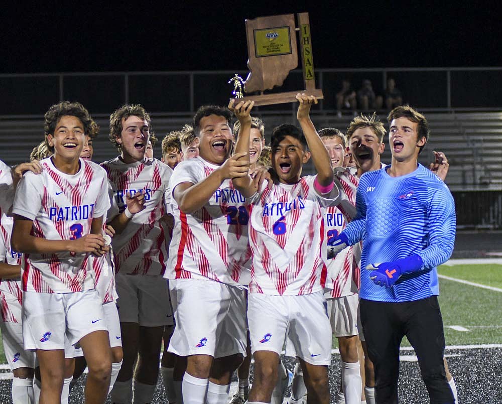 The Jay County High School boys soccer team, including in front from left, Aryan Montes, Emmitt Reynolds, Alan Ortiz, Dylan Marentes and Peyton Yowell, celebrate with the sectional championship trophy after knocking off the unbeaten host Eastbrook Panthers 3-2 (4-3) in a penalty kick shootout Saturday night. The win gave the Patriots their second title in three years and sends them to play at Park Tudor in the regional semifinal at 6 p.m. Thursday. (The Commercial Review/Ray Cooney)