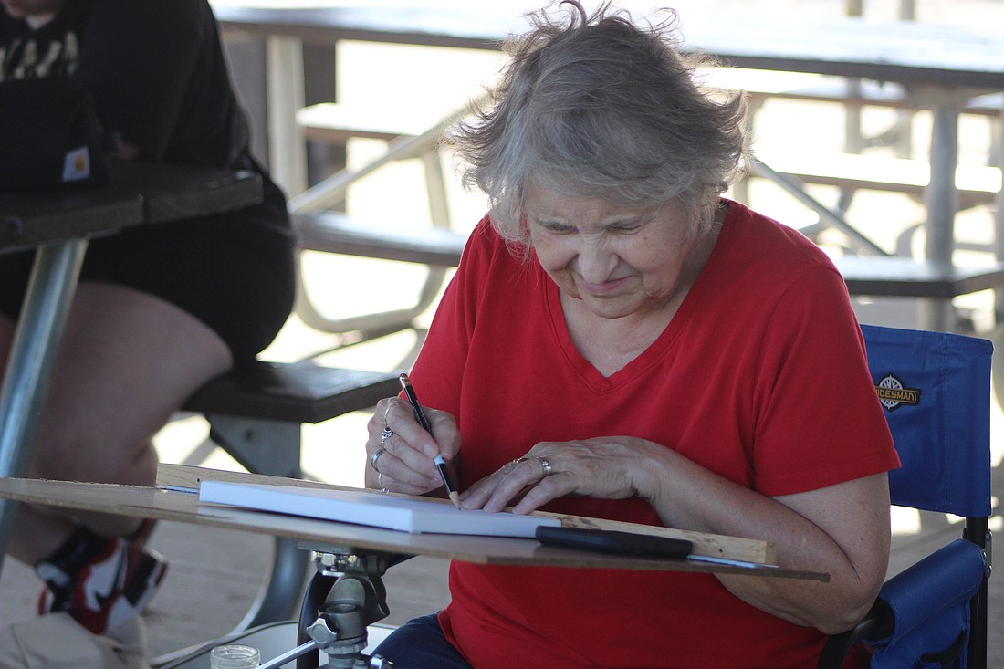 Delores Hart sketches out a design of the pond Friday afternoon at Hudson Family Park in Portland. The Alcove Artists’ Collective members spent their evening painting at the park. (The Commercial Review/Bailey Cline)