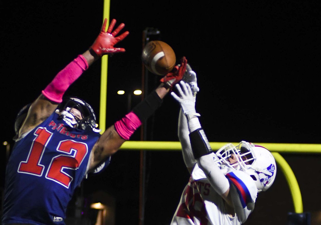 Jay County High School's Grant Wendel rises up to complete a pass, while Heritage's Braden Walter gets a hand on the ball to break up the play. While Wendel couldn't come down with the ball, he made two catches on a scoring drive in the third quarter. (The Commercial Review/Andrew Balko)