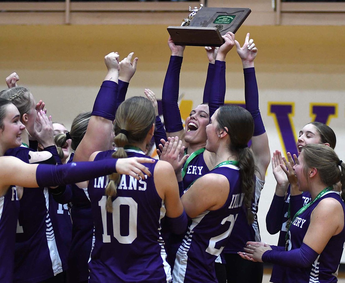 Fort Recovery High School’s Kayla Heitkamp holds up the OHSAA Division VI Southwest 2 District Championship trophy while her teammates celebrate around her on Saturday at Butler. The Indians swept Miami Valley Christian Academy to clinch their first regional appearance since 2020. (The Commercial Review/Andrew Balko)