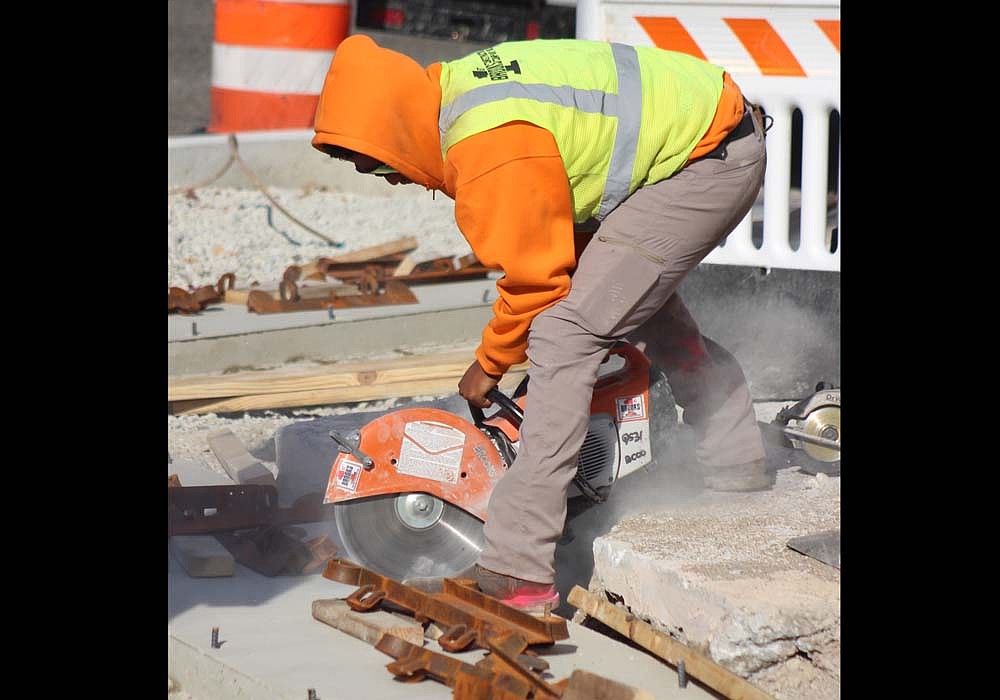 A construction worker cuts into concrete while working Wednesday on the northeast curb at the intersection of Meridian and Main streets in Portland. (The Commercial Review/Bailey Cline)