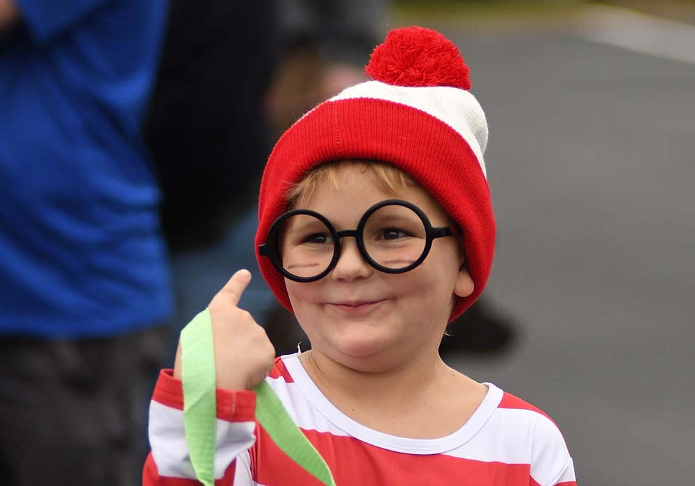 Eight-year-old Eli Edmundson provides a little assistance with answering the big question — “Where’s Waldo?” — as he points to himself visiting the Jay County Chamber of Commerce table during Thursday’s merchant trick-or-treat in Portland. Businesses and organizations gathered in the Jay Community Center and East Jay Elementary School parking lots for the event, which was moved from its traditional downtown location because of the ongoing construction on Meridian Street (U.S. 27). (The Commercial Review/Ray Cooney)