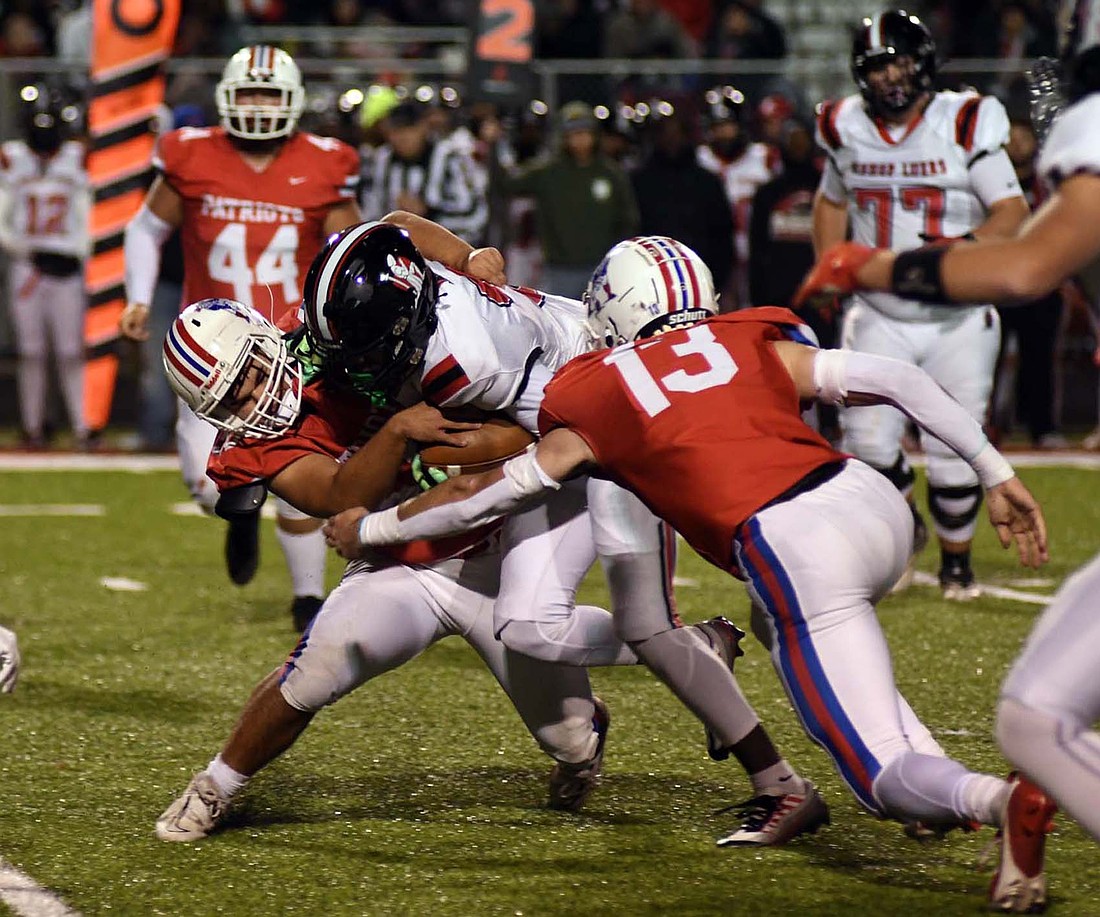 Jay County High School’s Joaquin Johnson and Lucas Strait (13) come together to tackle DaMeon Hogue of Bishop Luers in the sectional semifinal on Friday night. The Patriots saw their season come to a close with a 41-8 loss as they struggled to handle the Knights’ speed. (The Commercial Review/Andrew Balko)