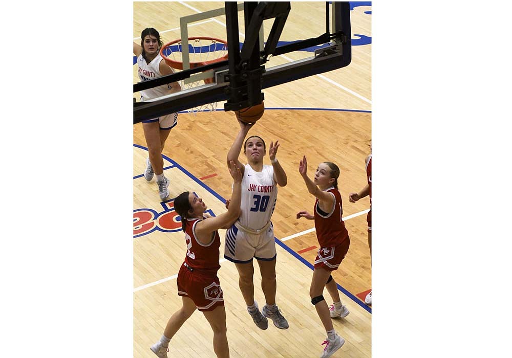 Elizabeth Brunswick of the Jay County High School girls basketball team powers up through Adams Central’s Izzy Isch (12) and Tenley Hendricks (1) for a layup during Friday’s 53-50 overtime victory. Brunswick scored all seven of Jay County’s points in overtime points en route to a career-high 21. (The Commercial Review/Andrew Balko)