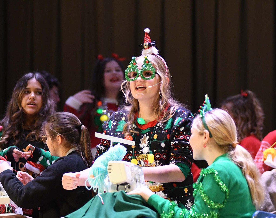 There were more Christmas activities Tuesday as the Jay County junior high choirs put on their Christmas program while Jay County Public Library offered gingerbread house decorating. Pictured above, members of the junior high choir, including Grace Huelskamp (center) portraying Marlo, perform in “A Christmas Yarn.” At right, Lizette and Dalila Lopez, 6, of Portland build a gingerbread house together Tuesday at the library. Patrons were invited to visit the Community Room to build the holiday staple with a wide variety of candies. (The Commercial Review/Ray Cooney and Bailey Cline)