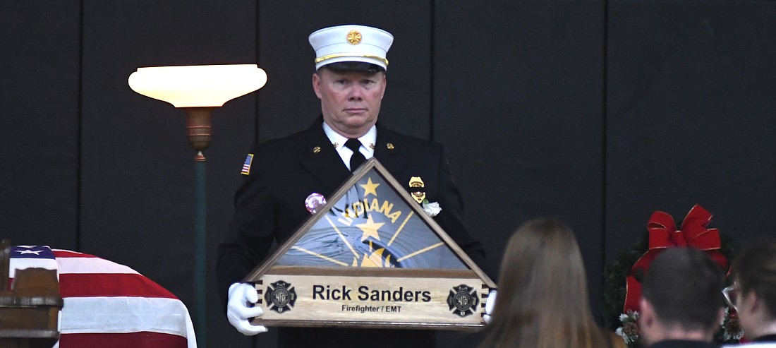 Winchester Fire Chief Scott Patterson holds an Indiana state flag during Sunday’s funeral for firefighter Rick Sanders at Winchester Fieldhouse. Hundreds gathered to remember Sanders, who died after going into cardiac arrest while responding to a fire Dec. 12. In addition to the flag, Indiana State Fire Marshal Steve Jones presented Sanders’ family with the Indiana State Fire Marshal's Meritorious Service Medal in his honor. (The Commercial Review/Ray Cooney)