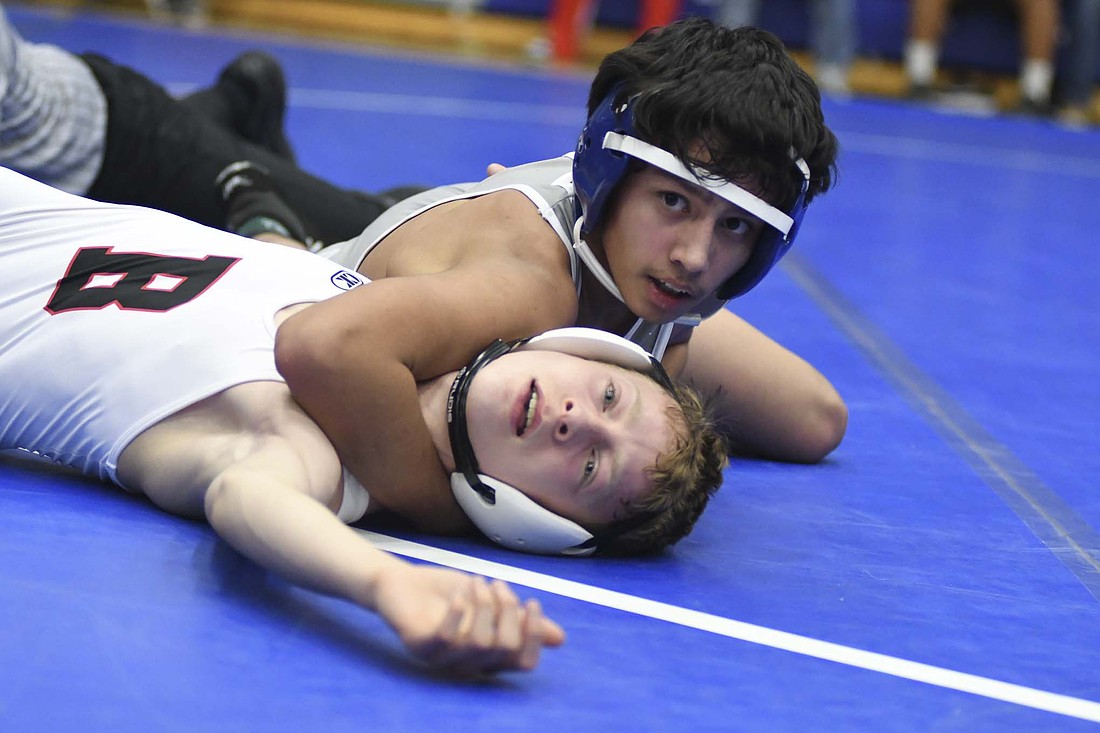 Jay County High School freshman Corbin Lothridge looks toward his coaches for guidance while trying to force Will Frettinger of Bluffton to the mat in the 106-pound championship match during Monday’s East Central Indiana Classic. Lothridge pinned Frettinger in the third period to earn one of the host Patriots’ five championships as they won the team title. (The Commercial Review/Ray Cooney)