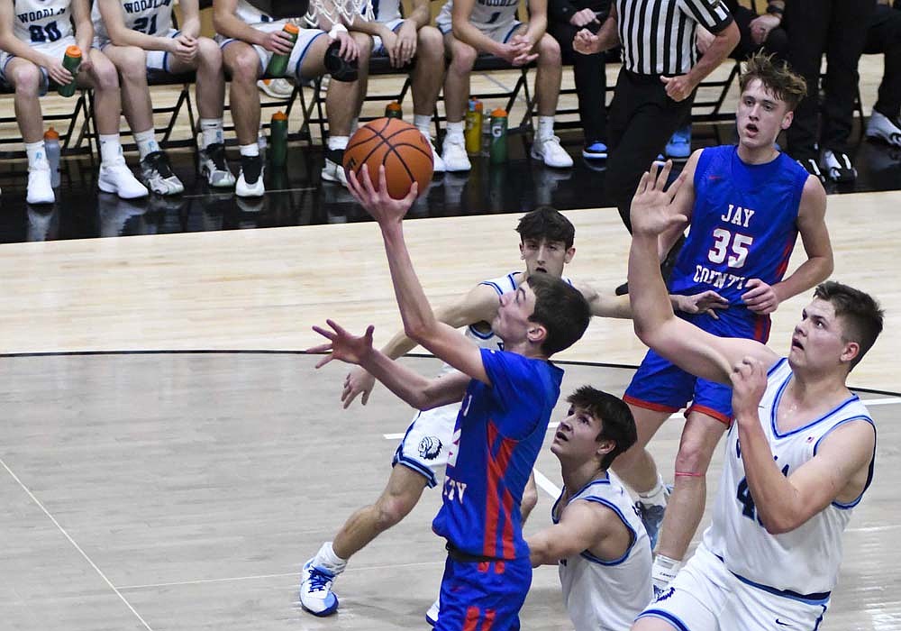 Jayden Comer of Jay County High School goes to the basket in front of a trio of Woodlan Warrior defenders during the first quarter of Friday’s Allen County Athletic Conference Tournament semifinal at Bluffton. Comer had 11 points to lead the Patriots, but they couldn’t overcome a 33-point night from Woodlan senior Trey Yoder. (The Commercial Review/Ray Cooney)