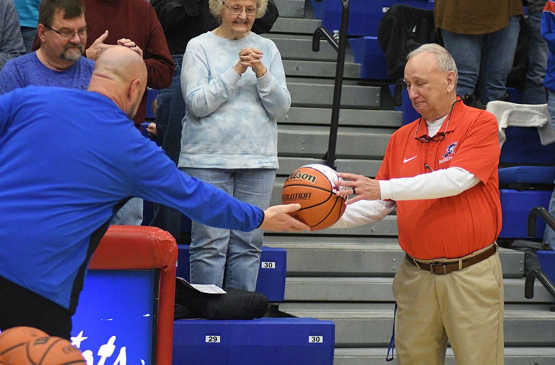 Jay County High School athletics director Alex Griffin hands Jerry Bomholt a commemorative basketball prior to the Jan. 31 matchup with Bluffton in celebration of the coach reaching 600 career wins 17 days earlier. Bomholt retired from being the Patriots head coach effective immediately on Tuesday after suffering a second health scare prior to Saturday's game at Blackford. (The Commercial Review/Ray Cooney)