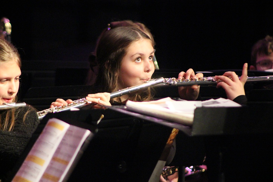 Jay School Junior-Senior High School and Fort Recovery Local Schools both held their winter band concert Sunday afternoon. Pictured above, fifth grader Victoria Bruns watches director Reid Knuth while playing her flute. Bruns and her fellow band members played selections from “Essential Elements for Band, Book 1.” Below, Ango Kato plays the tenor saxophone during the Jay County junior high and high school combined bands’ performance of the theme from “Mission Impossible.” (The Commercial Review/Bailey Cline and Ray Cooney)