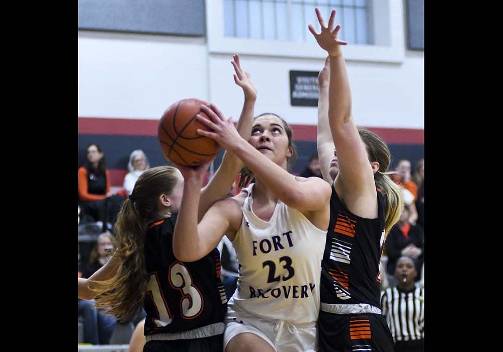 Bridget Homan of the Fort Recovery High School girls basketball team splits West Liberty-Salem’s Addie Wallen (13) and Ava Poppe during the OHSAA Division VI Southwest 2 District opener Tuesday. Homan scored a career-high 17 points to lift the Indians past WLSHS 40-31. (The Commercial Review/Andrew Balko)