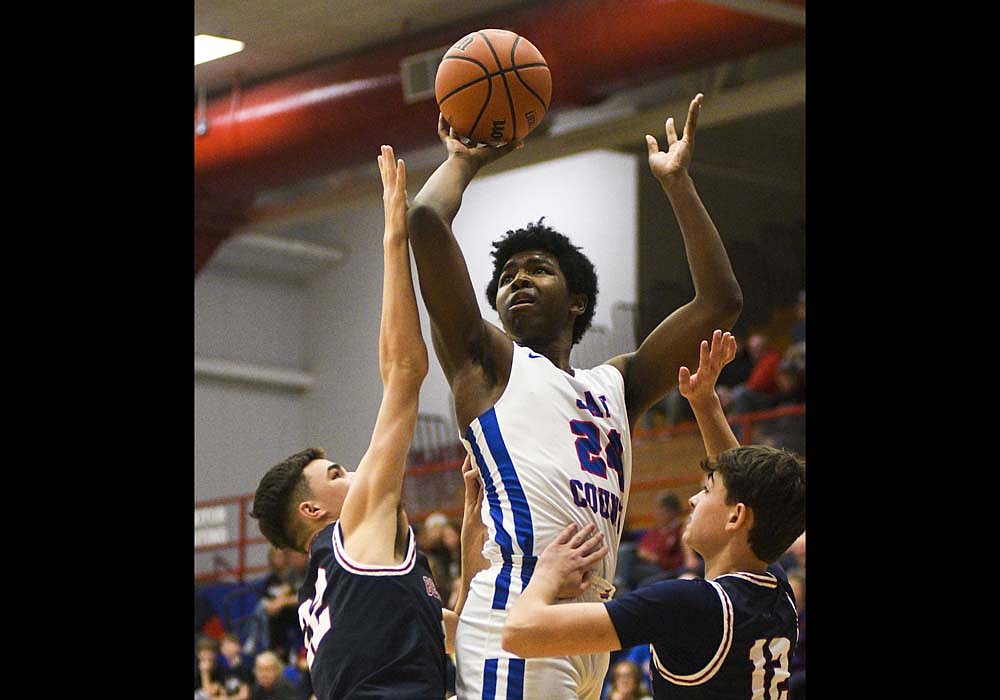 Jay County High School senior Caden Gambill puts up a shot against Derick Vogel (left) and Luke Summers of Bellmont late in the game Friday. Gambill split a pair of free throws for his first varsity points in the Patriots’ 72-46 victory. (The Commercial Review/Ray Cooney)